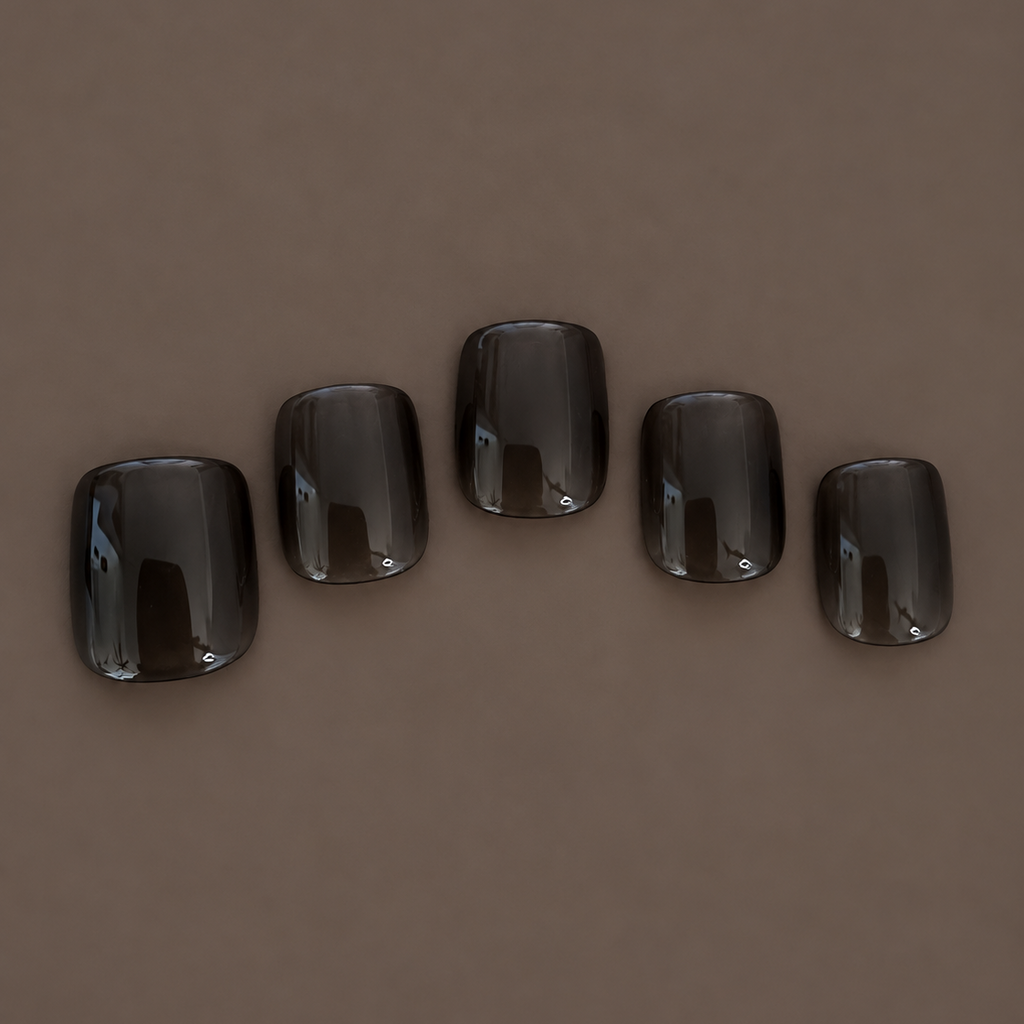 Five Extra Smoke extra-short square press-on nails with a translucent charcoal-black finish, arranged on dark taupe