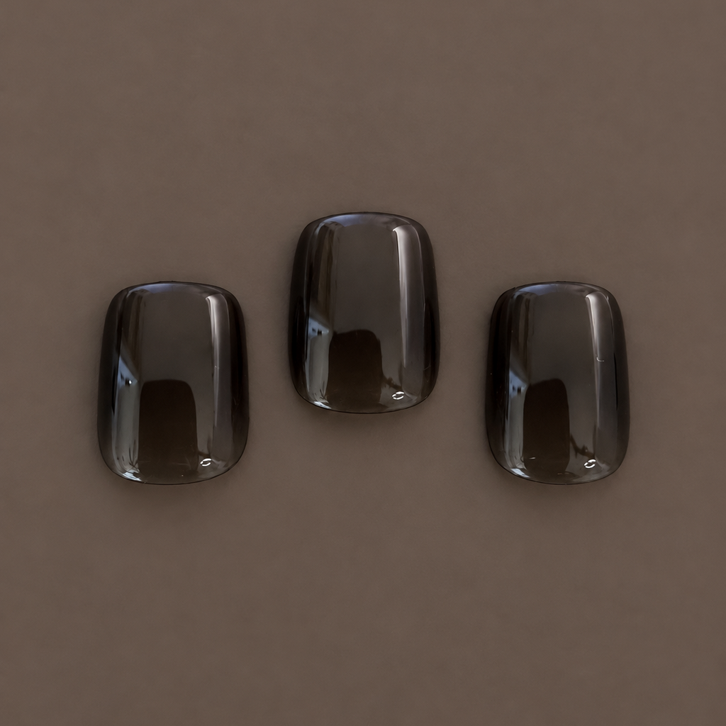 Close-up of three Extra Smoke glossy smoky-black jelly press-on nails by U.P.O.N on a dark taupe background